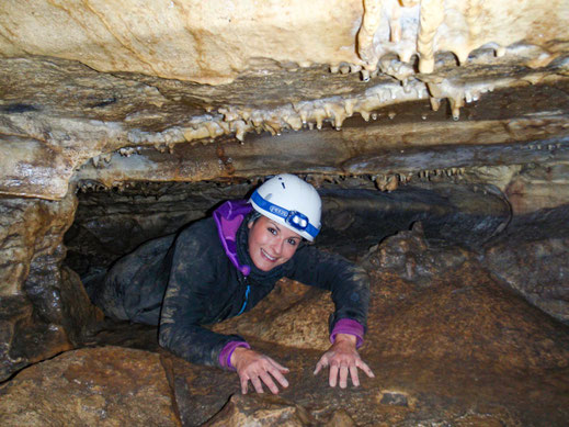 Person mit Helm und Stirnlampe kriechend in der Gustav-Jakob-Höhle in der Schwäbischen Alb