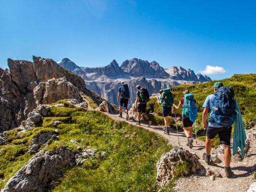 Dolomiten-Durchquerung: Gruppe junger Wanderer auf Mehrtagestour mit Blick auf die Sellagruppe