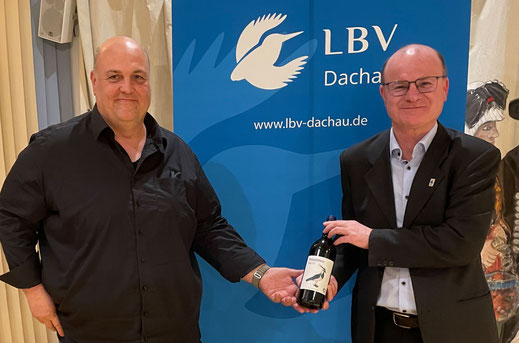 Der Kreisvorsitzende überreicht dem Landesvorsitzenden eine Flasche Wein aus bilologischem Anbau mit dem Kiebitz (Vogel des Jahres 2024) im Etikett.