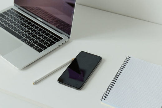 チェックシートに書き込む社員の手。電卓、眼鏡、キーボード、マウス。