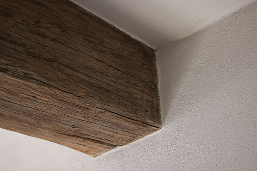 weißer Lehmputz an nicht geölten Holzbalken