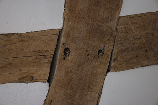 Fachwerkbalken in Kreuzform umgeben von weißem Lehmputz