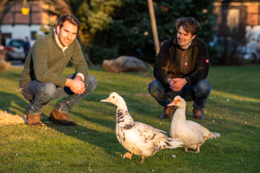 Die beiden Brüder Tilman und Hans-Frederik Berg mit zwei Flugenten auf der Wiese