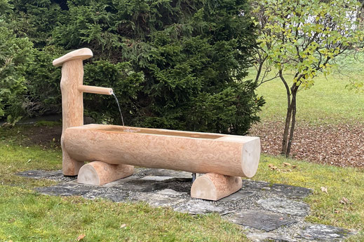 Brunnentrog aus Holz aus Lärche aus Rundholz mit Brunnenstock als Holzbrunnen im Garten mit fliessendem Wasser