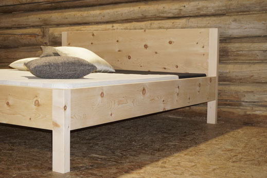 Handgefertigtes Arvenbett aus Massivholz mit natürlicher Holzmaserung.