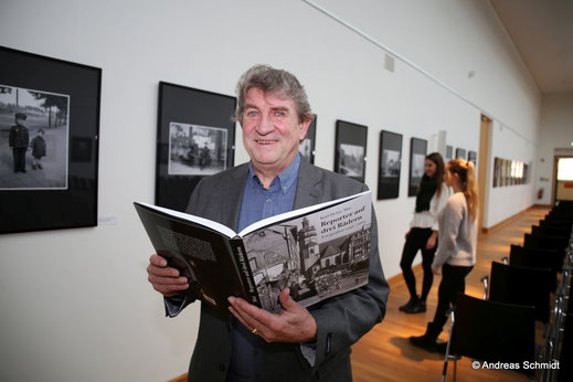Portrait Karl Detlef Mai mit Buch in der Ausstellung