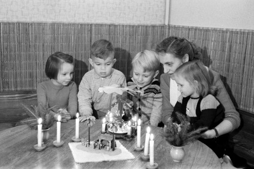 Kindergruppe am Tisch mit Weihnachtspyramide und Erzieherin