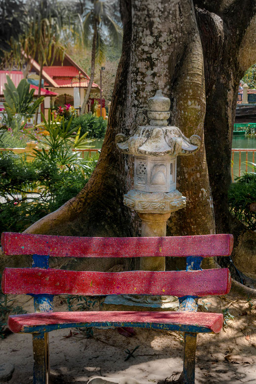 Rote Ruhebank unter Bäumen im Oriental Village auf Langkawi