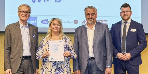 Stolze Absolventin mit Urkunde neben Gratulanten