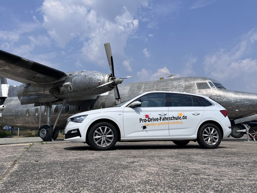 Fahrschul Auto vor Flugzeug in Köln