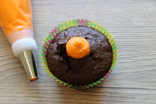 pipe orange frosting into cupcakes