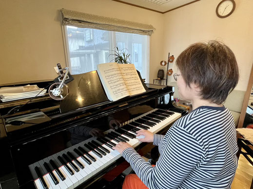 ピアノレッスン中に演奏する40代女性の後ろ姿