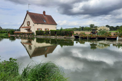 Ein altes Schleuserhäuschen spiegelt sich im Wasser des Canal du Centre. 