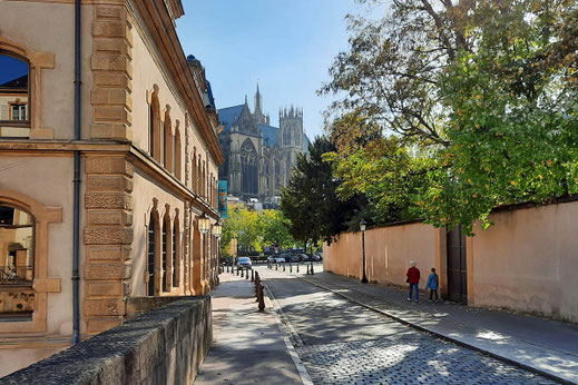 Eine schmale Straße mit Kopfsteinpflaster führt in Richtung einer mittelalterlichen Kathedrale.