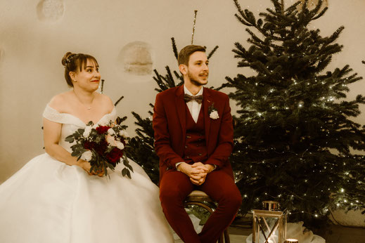 Mariés assis devant des sapins pour une décoration de mariage thème hiver et Noël près de Nantes
