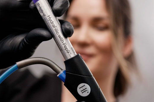 Kosmetikerin bei Canisius Cosmetic in Köln führt die HydraFacial Behandlung mit dem HydraFillic with Pep9 Booster durch.