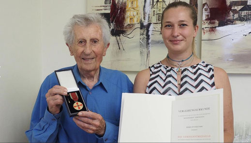 Otto Holynski präsentiert stolz seine Verdienstmedaille, seine Enkelin Lara Holynski die Verleihungsurkunde; Foto: Tabea Goppelt, Mainpost