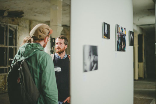 a group of people watching the exhibition with one man looking to the photographer
