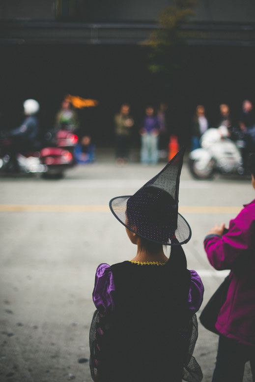 a girl in a wizard costume watching a Halloween parade