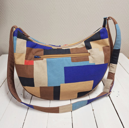 Sac bandoulière demi-lune artisanal cousu à la main par Märchenland. Toile de coton géométrique marron et bleu, 3 poches, bandoulière réglable. Pièce unique.