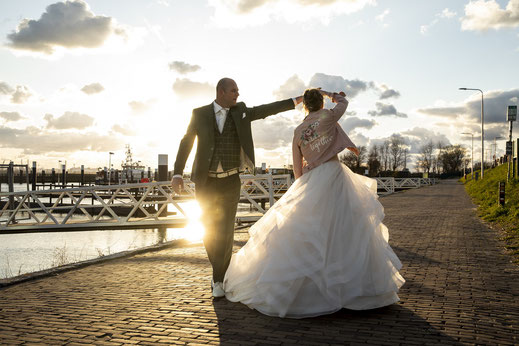 bruid danst in custom jasje over trouwjurk, bruidszaak La Nova trouwfotograaf Trouwfoto.nl