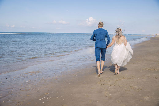 bruid en bruidegom lopen door barnding op het strand mooie zomerdag.