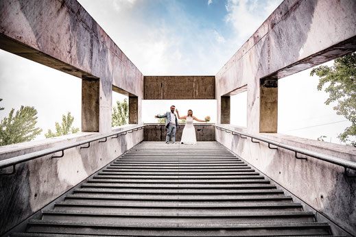 Das Brautpaar steht auf einer hohen Treppe auf der Zeche Zollverein in Essen nach der Hochzeit.