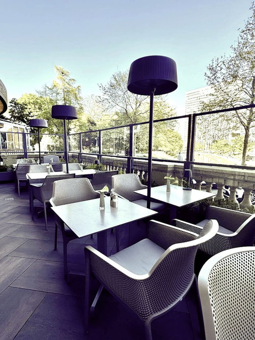 Moderne Terrassengestaltung mit wetterfesten Möbeln und transparentem Windschutz für ungestörten Blick auf das Stadtpanorama und Wasser