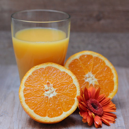 jus d'orange avec une orange coupée en deux et une fleur