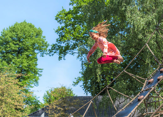 Kitafoto - Mädchen springt vom Klettergerüst