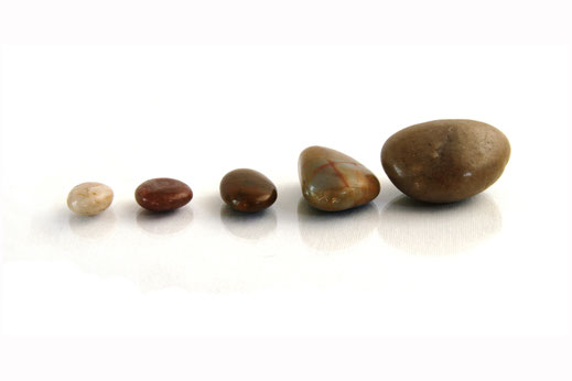 Eine Reiher von 5 kleinen Steinen, die nebeneinander liegen. Links liegt der kleinste, die Steine werden nach rechts hin immer größer.