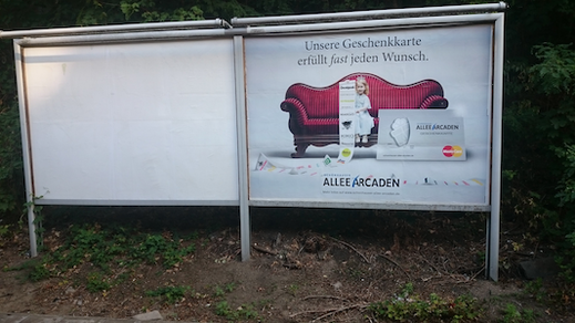 Werbeplakat von 2015: Ein Mädchen hält eine Liste von Unternehmenslogos. Der Text 'Unsere Geschenkkarte erfüllt fast jeden Wunsch' verdeutlicht, wie #zusammentun dir hilft, auf dich selbst zu vertrauen und Selbstwirksamkeit zu entwickeln.