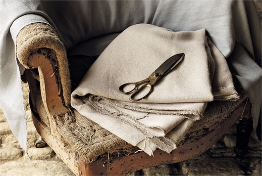 Carcasse de fauteuil crapaud, sans tissu, sur lequel on voit la garniture en crin piquée main à l'ancienne comme Ecoute bergère tapissier le pratique, une paire de ciseaux de tailleur est posée sur un tissu plié sur l'assise