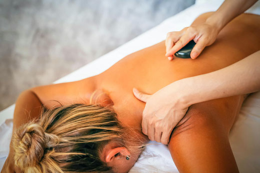 Eine Frau lässt sich mit warmen Vulkansteinen bei der Hot-Stone-Massage verwöhnen