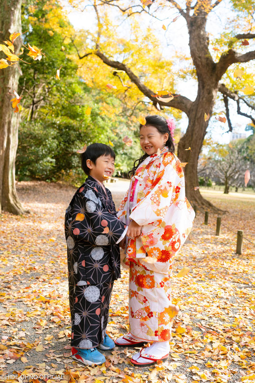 Smiling kids in colorful kimono under golden ginkgo leaves — capturing joyful autumn moments in Tokyo.