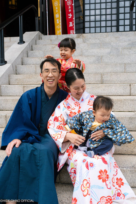 Family with two young children in kimono sitting on temple steps in Tokyo during winter