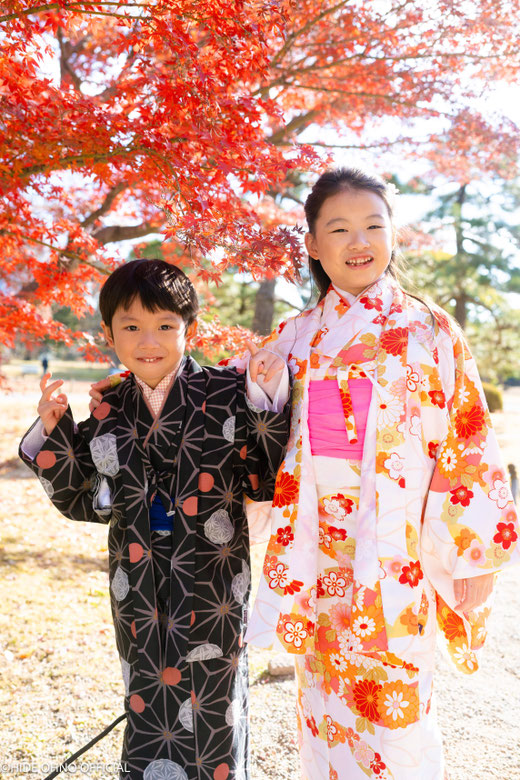 Mother in red kimono holding child and smiling in front of Senso-ji temple in Asakusa, Tokyo