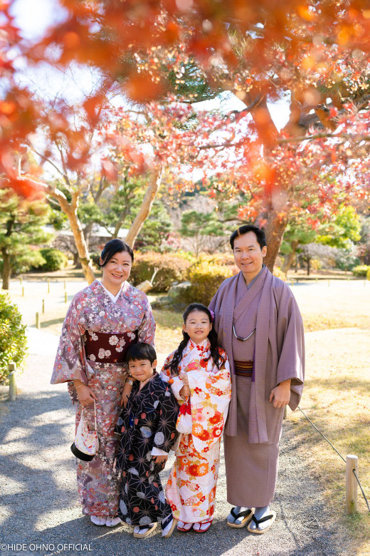 Family wearing kimono during an autumn photoshoot in Tokyo garden with colorful leaves