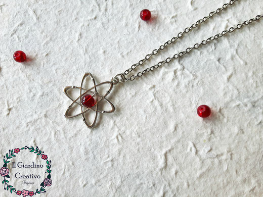 Collana Atomo, realizzata con ciondolo atomo decorato con perlina in vetro cracklè rossa a simboleggiare il nucleo.