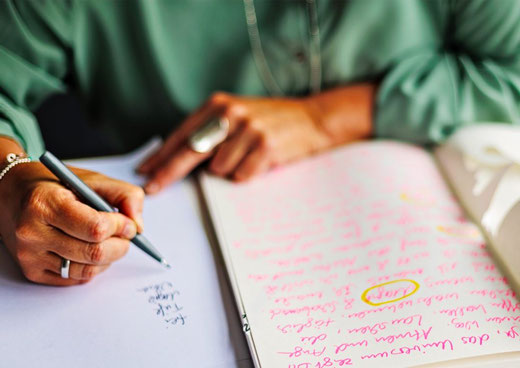 Eine Frau, die etwas in ein Notizbuch schreibt.