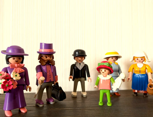Playmobil-Figuren vor einer weißen Tapete.