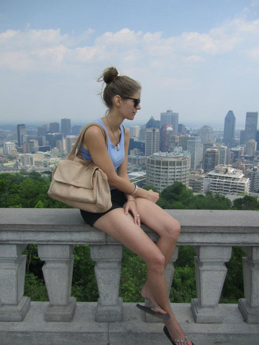 Frau sitzt auf einer Brüstung vor der Stadt Vancouver am Mont Royal