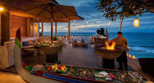 Ein Koch grillt Gourmetgerichte in einem Klippenrestaurant in Uluwatu.