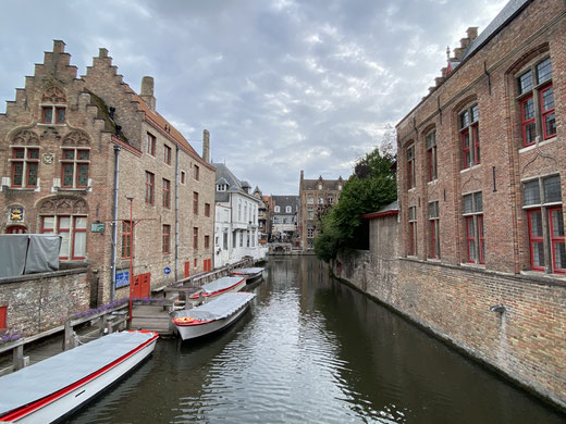 barche nel canale di Bruges con ai lati edifici tipici di mattoni rossi