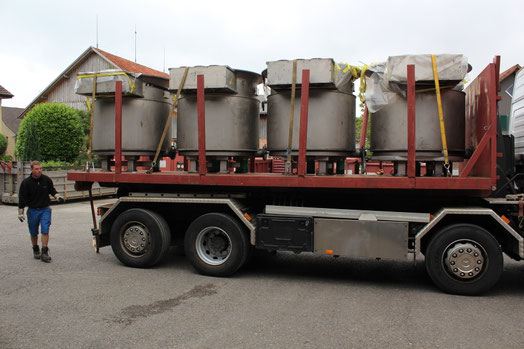 Ein weisser Lastwagen von Gerster Recycling steht auf einem Freigelände mit Transportbrücke. Im Hintergrund sind mehrere grosse rote Abfallcontainer mit dem Logo von Gerster Recycling zu sehen. Das Bild zeigt einen Recycling- und Abfallentsorgungsbetrieb.