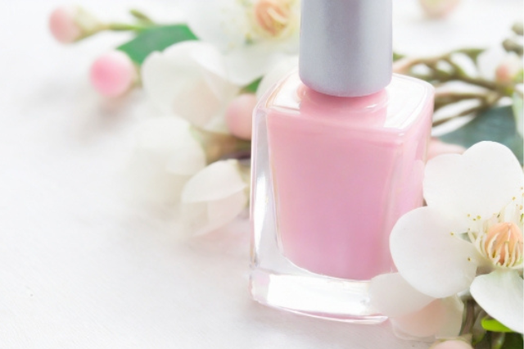 桃の花と薄いピンク色のマニキュアの瓶。