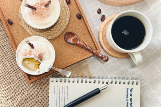 リングノートと万年筆。コーヒーの入ったマグカップ。クリームブリュレがのったトレイ。