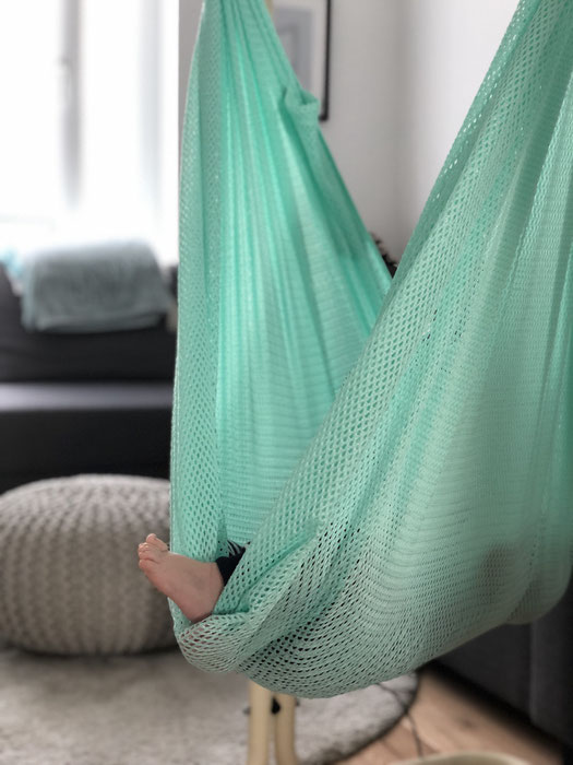 Nackte Babyfüße in der Hängematte der Federwiege für Babys