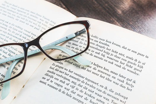 ページが開かれた洋書のうえに置かれた眼鏡。