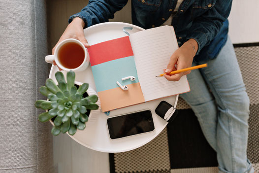 Mesa con un cuaderno, un té y auriculares, simbolizando la práctica diaria del español como parte de una rutina relajada.